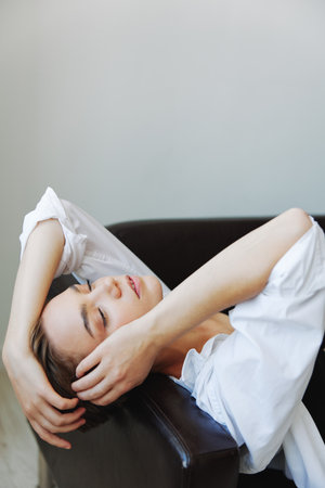 Women lying at home on the couch portrait with a short haircut in a white shirt, smile, depression in teenagers, home holidayの写真素材