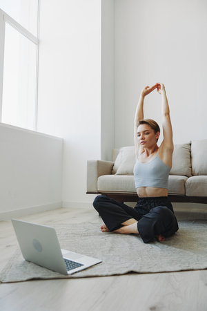 Woman exercising at home by video workout online, meditation and stretching, mental healthの写真素材