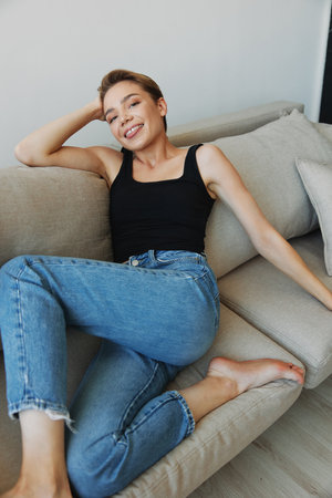 Young woman with short haircut hair having fun at home on the couch smile and happiness, vacation at home, natural posing without filters, free copy spaceの写真素材