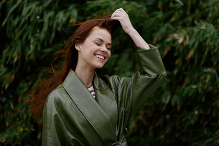 Portrait of happiness woman with red flying hair smile with teeth walking in the city in the park against a backdrop of green bamboo leaves, spring in the cityの写真素材