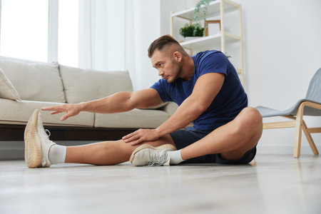 Man sportsman training at home, stretching exercises for arm, leg and back muscles, strong body and correct posture, the concept of health and beautyの写真素材