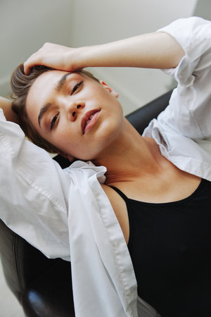 Women lying at home on the couch portrait with a short haircut in a white shirt, smile, depression in teenagers, home holidayの写真素材