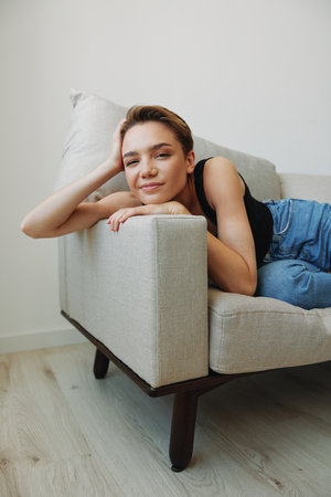 Young woman with short haircut hair having fun at home on the couch smile and happiness, vacation at home, natural posing without filters, free copy spaceの写真素材