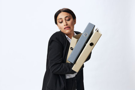Business woman with a folder of documents in her hands in a black business suit and glasses shows signals gestures and emotions on a white background, work freelancer online trainingの写真素材