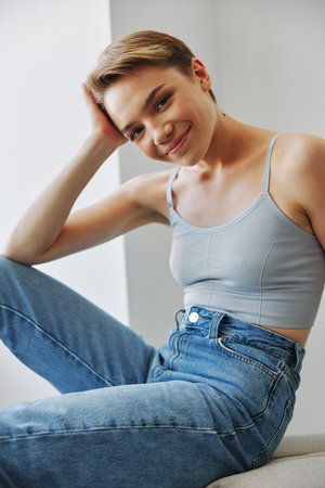 Young woman with short haircut hair having fun at home on the couch smile and happiness, vacation at home, natural posing without filters, free copy spaceの写真素材