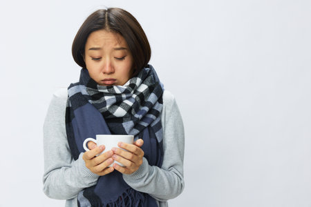 Asian woman cold flu holding a mug of tea smile in plaid with fever sick of the virus on a white background, copy spaceの写真素材