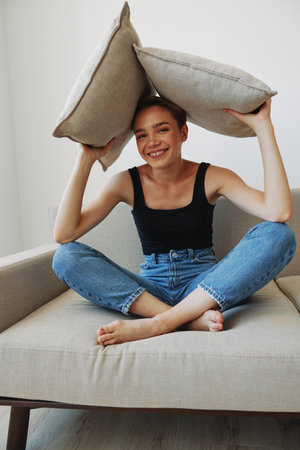 Young woman with short haircut hair having fun at home on the couch smile and happiness, vacation at home, natural posing without filters, free copy spaceの写真素材