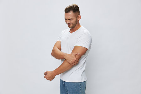Man arm pain, muscle and ligament sprain in sports, inflammation and injury, in white T-shirt on white isolated background, copy spaceの写真素材