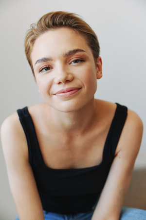 Young woman with short haircut hair having fun at home on the couch smile and happiness, vacation at home, natural posing without filters, free copy spaceの写真素材