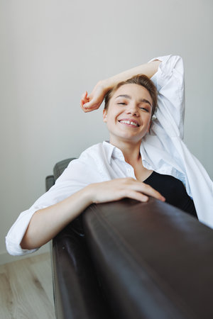 Women lying at home on the couch portrait with a short haircut in a white shirt, smile, depression in teenagers, home holidayの写真素材
