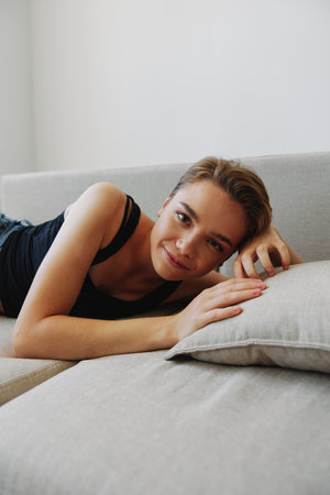 Young woman with short haircut hair having fun at home on the couch smile and happiness, vacation at home, natural posing without filters, free copy spaceの写真素材