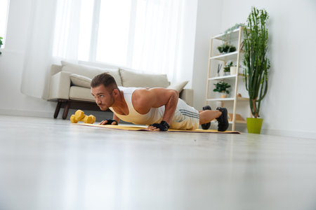 Man sports home training on the floor on a mat with dumbbells, exercises for muscle growth, pumped...