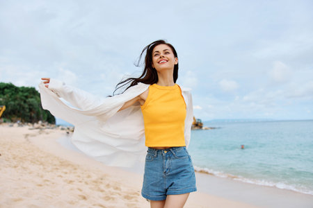 Portrait of a happy woman smile with teeth with long hair brunette walks on the sea beach summer travel and feeling of freedom, balanceの写真素材