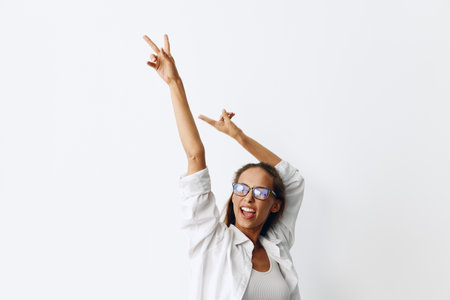 Woman portrait with tanned skin wearing vision goggles on a white background smiling with teeth and hands up in joyの写真素材
