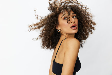 Beautiful woman with curly afro hair posing on a white isolated background smile happiness in jeans and black top emotion, hand signs, copy spaceの写真素材