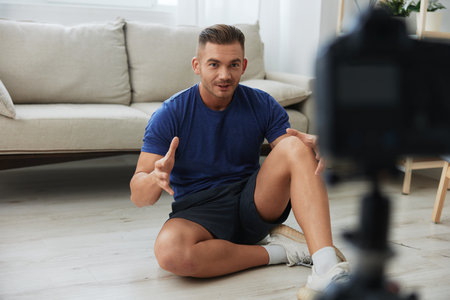 Man athlete blogger records exercise training on the body at home on camera, sports blogger bodybuilder, the concept of health and beautyの写真素材