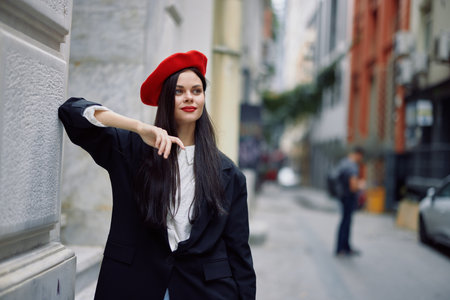 Woman standing near a wall in the city wearing a stylish jacket and red beret with red lips, travel and leisure, French style of dress.の写真素材