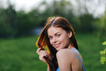 A woman in the spring nature smile with teeth touching hand long natural hair and happy, the concept...