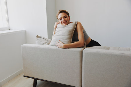 Happy woman smile lying at home on the couch relaxing on a weekend at home with a short haircut hair without filters on a white background, free copy spaceの写真素材