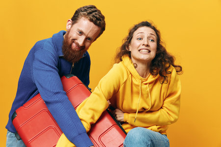 Woman and man smiling, suitcases in hand with yellow and red suitcase smiling merrily and crooked,...