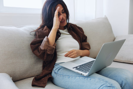 Woman freelancer on day off sitting on sofa with laptop at home online video chat call, smile