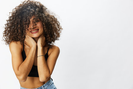 Beautiful woman with curly afro hair posing on a white isolated background smile happiness in jeans and black top emotion, hand signs, copy spaceの写真素材
