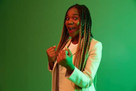 African american woman portrait business smile on green background in neon light, color mixed light, bright colors. Beauty African American woman with pigtails emotions.の写真素材