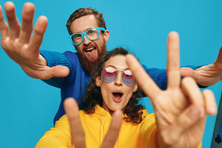 A woman and a man fun couple cranking and showing signs with their hands smiling cheerfully, on a blue background, The concept of a real relationship in a family.の写真素材