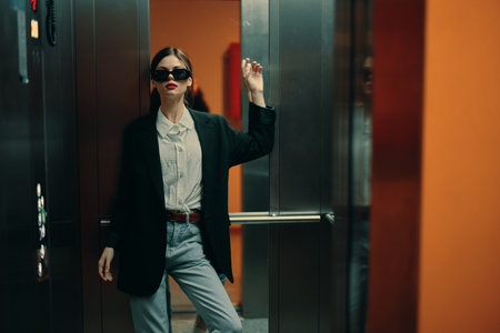 Stylish woman in black jacket and sunglasses posing in elevator, fashion model, dark cinematic light and color, glamor vintageの写真素材