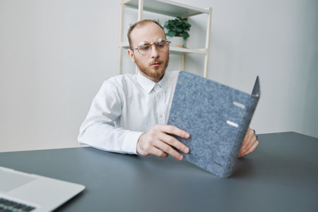 A man in a wheelchair, a businessman in the office works at a laptop, writing down a plan in a notebook, thoughtfulness, integration into society, the concept of working a person with disabilitiesの写真素材