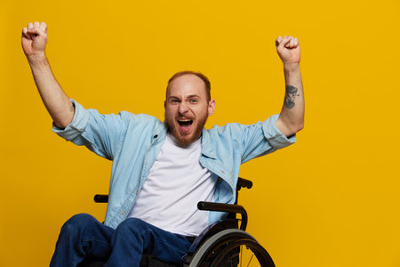 A man in a wheelchair smile and happiness, thumb up, with tattoos on his hands sits on a yellow studio background, the concept of health a person with disabilitiesの写真素材