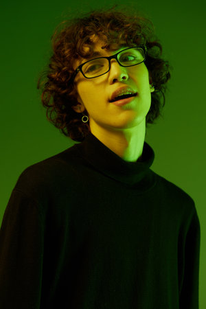 Man young man portrait close-up portrait in glasses fashion smile, hipster lifestyle, portrait green background mixed neon light, copy spaceの写真素材