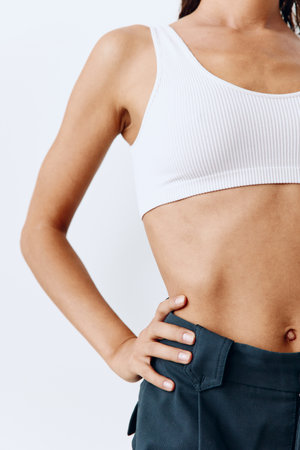 A woman with a beautiful body and tanned skin poses in white on a white background in her studio wearing home clothes and smiling beautifully with her teethの写真素材