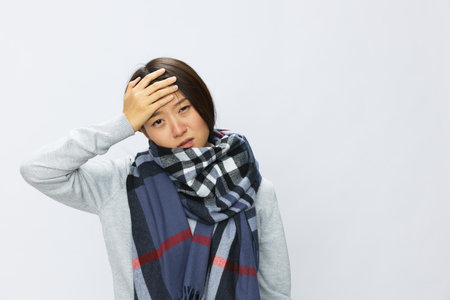 Asian woman cold flu raised hands from headache with fever sick from virus on white background, copy spaceの写真素材
