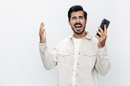 Close-up portrait man talking on the phone anger dissatisfaction and annoyance on a white isolated background, fashionable clothing style, copy space, space for textの写真素材