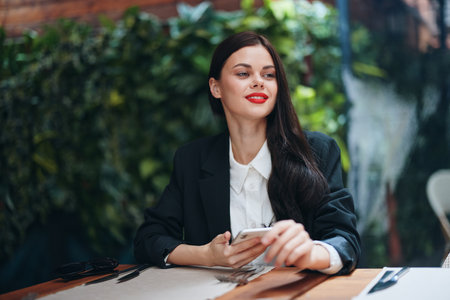 Fashion woman blogger tourist sits in a cafe with a phone in her hands reads a message, mobile communication and the Internet in travel spring, video call, freelance work online, smileの写真素材