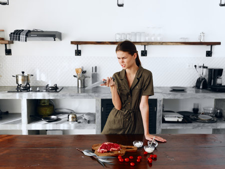 Sad angry woman standing in Stylish minimalist kitchen interior with natural elements in wood and stone design with fresh produce for dinner on the table, copy place, homemade food in a clean roomの写真素材