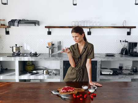 Sad angry woman standing in Stylish minimalist kitchen interior with natural elements in wood and stone design with fresh produce for dinner on the table, copy place, homemade food in a clean roomの写真素材