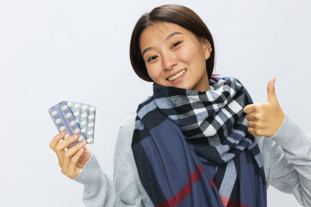 Asian woman smile cold flu holding medicine and pills in plaid with fever sick of the virus on a white background, copy spaceの写真素材