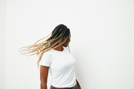 Portrait african american woman in white t-shirt smiling dancing with afro pigtails smile, flying hair, white background. Soft warm colors.の写真素材
