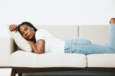 Happy african american woman sleeping at home on the sofa, rest and vacation smile, light background, daytime sleep, fatigue depression. Relaxed home lifestyle, day off.の写真素材