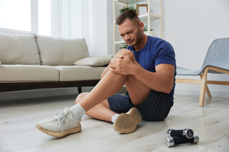 Man athlete pain and injury back arm and leg at home, sports injury bodybuilder, concept health and beautyの写真素材
