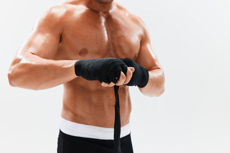Man athletic bodybuilder poses in boxing gloves with nude torso abs in full-length background,...