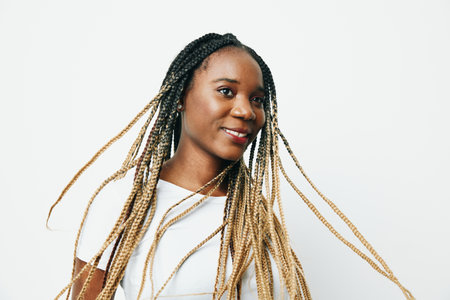 Portrait african american woman in white t-shirt smiling dancing with afro pigtails smile, flying hair, white background. Soft warm colors.の写真素材