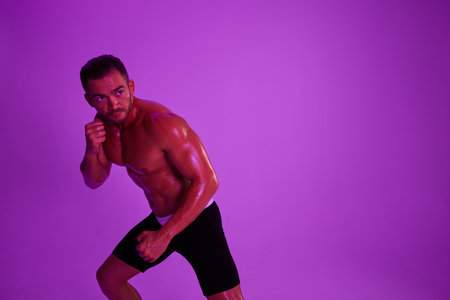 Man athletic body bodybuilder in briefs with nude torso abs full-length in the background fitness classes, purple colored light. Advertising, sports, active lifestyle, competition, challenge concept.の写真素材