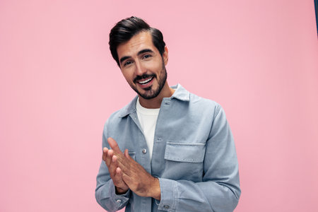 Fashion portrait of a brunette man with a beard on a pink background in a white T-shirt with a smile and joyful emotion on his face, copy spaceの写真素材