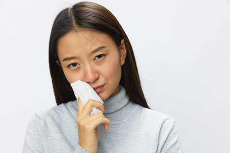 Sad Asian woman holding hand with handkerchief and coughing up flu and cold, stuffy nose viral disease asthma and allergies covid 19, white backgroundの写真素材