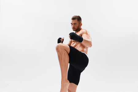 Man athletic bodybuilder poses in boxing gloves with nude torso abs in full-length background,...