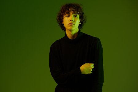 Man smile fashion and style accessories model with curly hair, stylish hairstyle, hipster dance teen lifestyle, portrait green background mixed neon light, copy spaceの写真素材