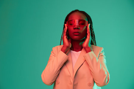 African american woman smile and fashion wearing glasses green background in neon light color mixed light, bright color dancing, futuristic party. Beauty African American woman with pigtails emotions.の写真素材